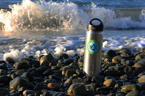 Reusable TAP water bottle on a beach. Photo: Jonathan Burnham, Wildland Adventures.